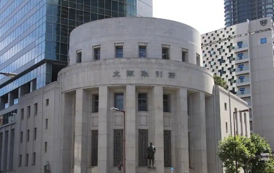 Round, neoclassical stone building with tall pillars and a statue in front, in a modern city street.
